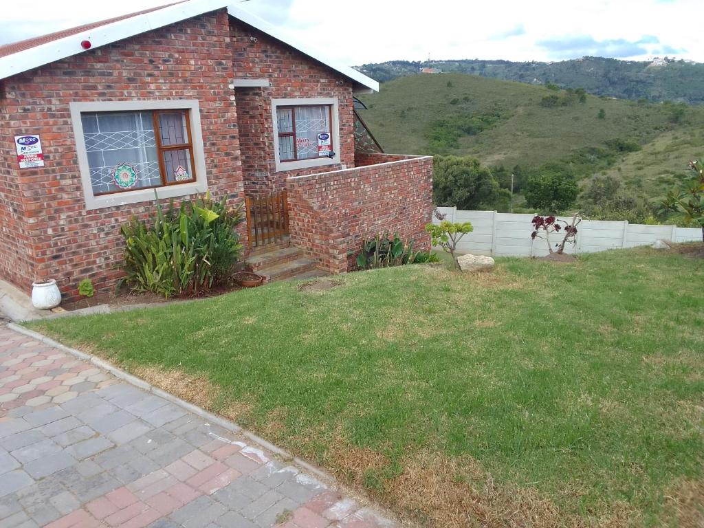 a brick house with a yard and a fence at Green Pastures in Great Brak River