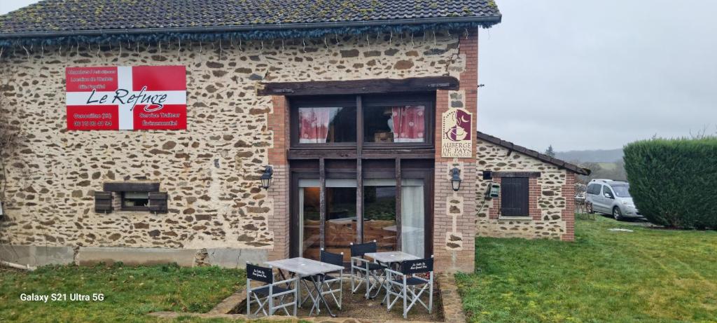 a building with tables and chairs outside of it at Le Refuge in Genouillac