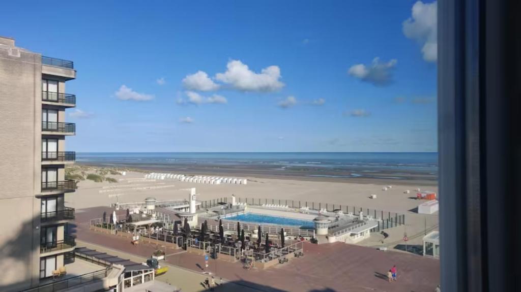 a view of a beach with a pool and a building at Modern appartement - Zeezicht - Perfecte ligging in Koksijde