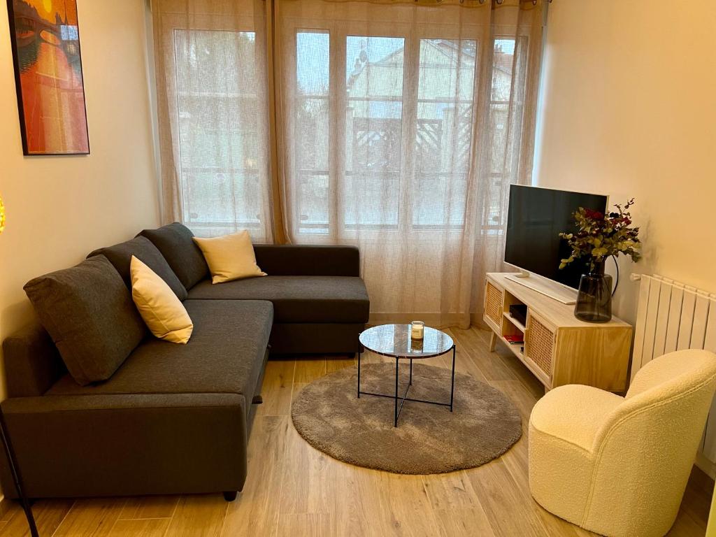 a living room with a couch and a television at La Résidence Alpha Viroflay 002 - 1 chambre - 4 pers in Viroflay