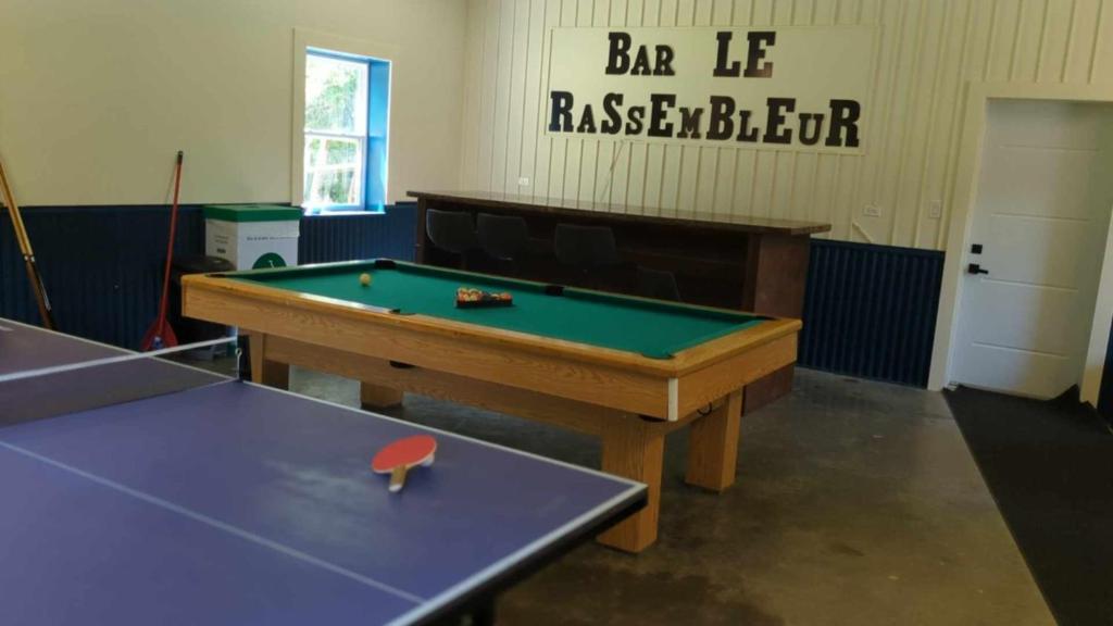 a room with a ping pong table and a sign at Chalet le Rassembleur in Racine