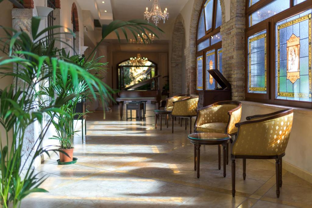 un vestíbulo con sillas y plantas en un edificio en Hotel Antico Monastero, en Toscolano Maderno