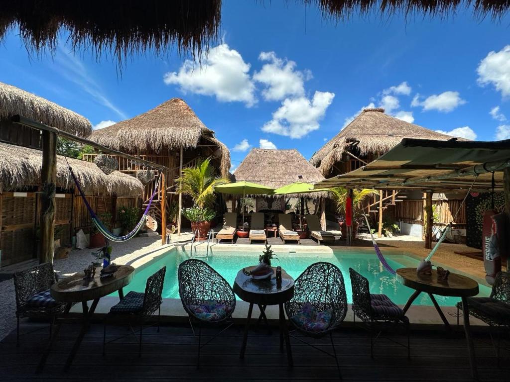 una piscina en un complejo con sillas y un columpio en Hotel Jungla y Estrellas, en Cobá