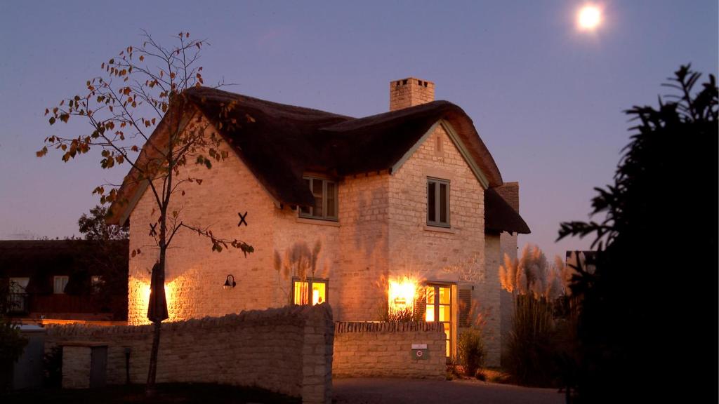 a large brick house with lights on at Moorhens in Somerford Keynes