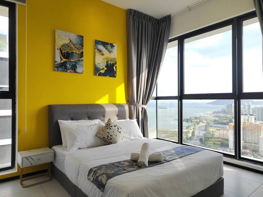 1 dormitorio con 1 cama grande y pared amarilla en Seaview Infinity Pool/ 40th/ 10pax/ 3Rooms 2Carpark, en Jelutong