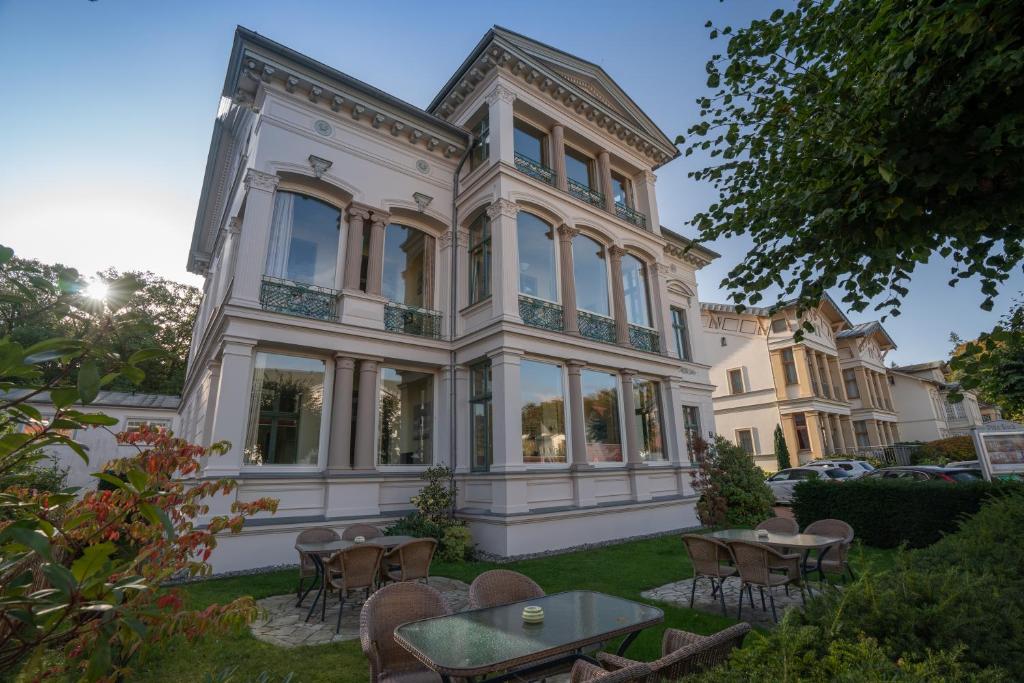 ein großes Haus mit Tischen und Stühlen davor in der Unterkunft Villa Stock Appartement mit großer Veranda in Heringsdorf