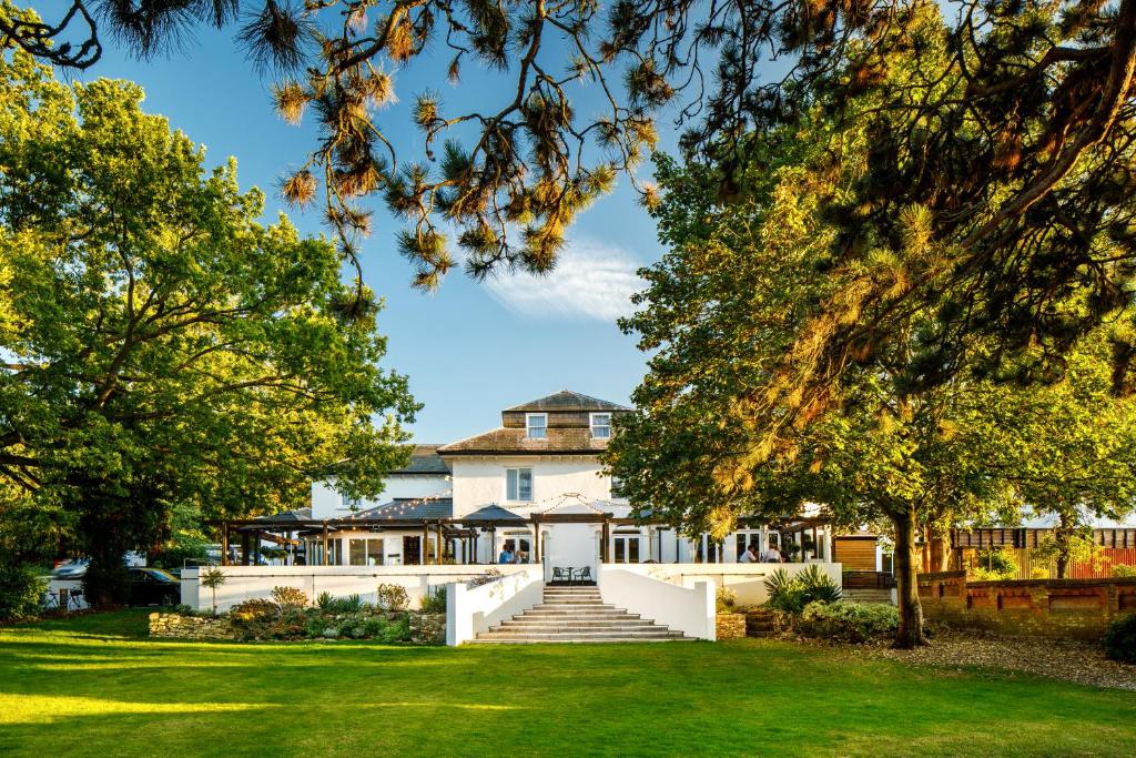 an exterior view of a large white house with trees at Mercure Oxford Hawkwell House Hotel in Oxford