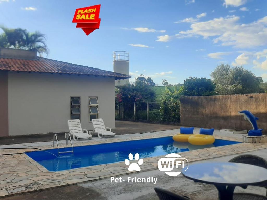 een zwembad in een achtertuin met een tafel en stoelen bij chácara Gato de Botas in Socorro