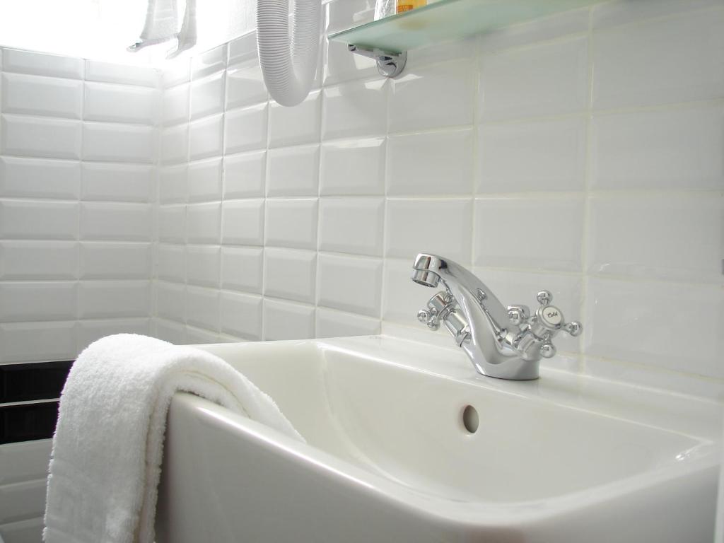 bagno bianco con lavandino e asciugamano bianco di Hotel Le Charleston a Le Mans