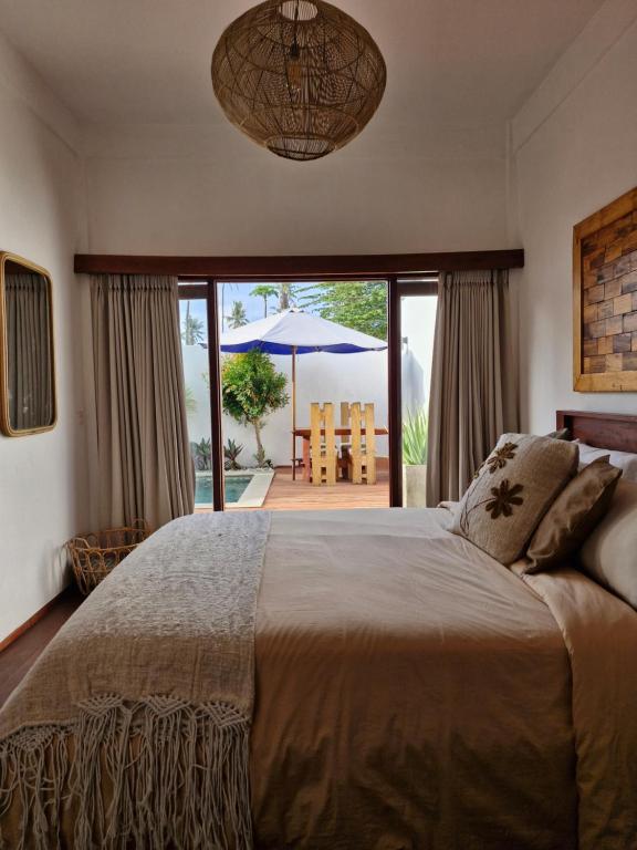 a bedroom with a large bed and an umbrella at The Sanctuary -Private pool villas in Gili Islands