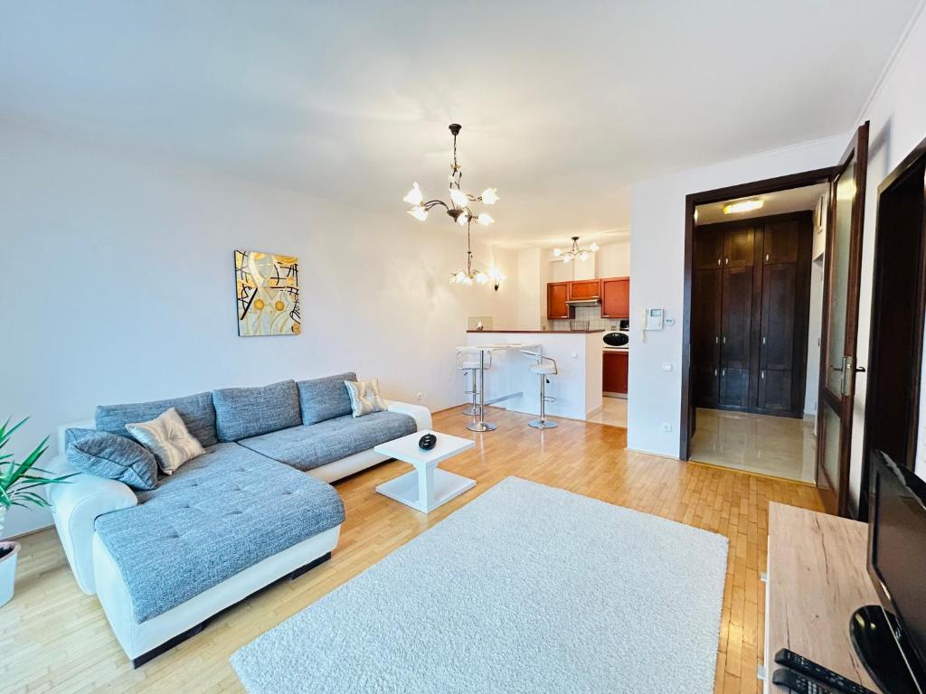 ein Wohnzimmer mit einem blauen Sofa und einer Küche in der Unterkunft BP Kazinczy Centrum Prime Suites in Budapest