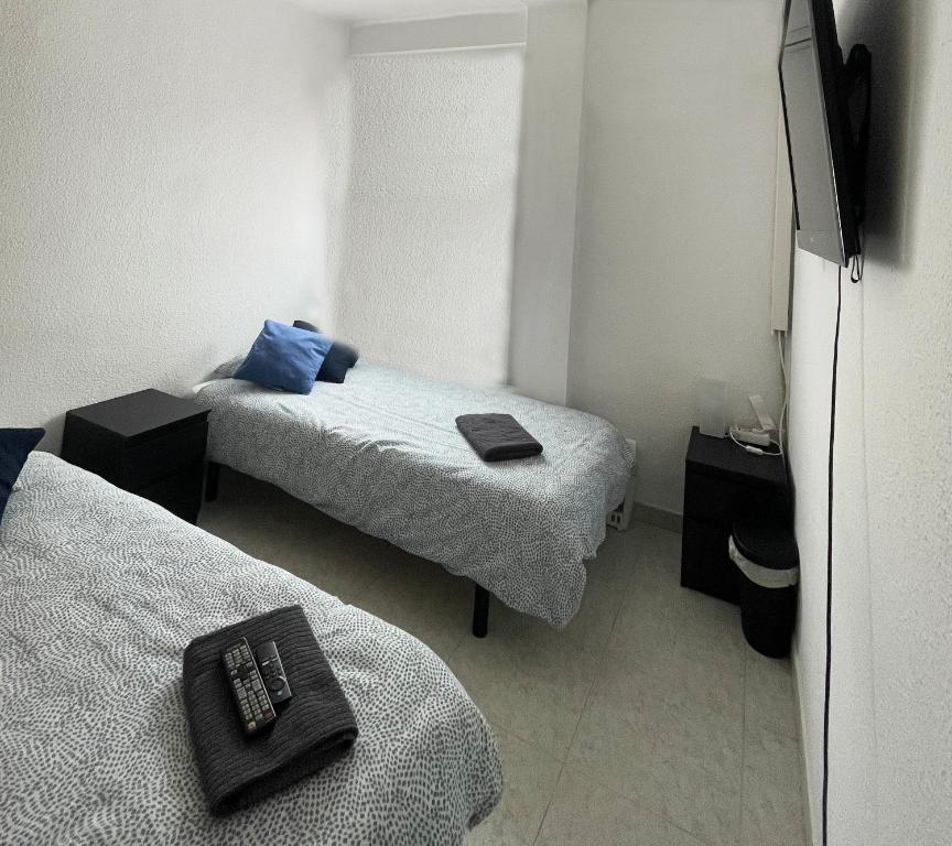 um pequeno quarto com 2 camas e uma televisão em Piso Aeropuerto - Estadio em Madri