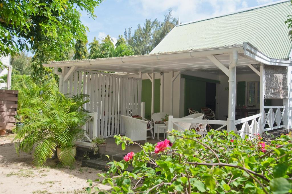 Cabaña con porche con sillas y flores en La Case Creole, en Roches Noires