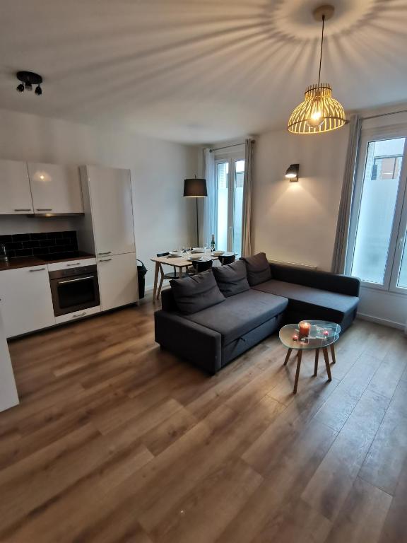 a living room with a black couch and a table at *Appartement Moderne/2 minutes du métro* in Saint-Ouen