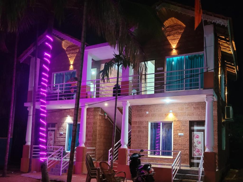 a man on a motorcycle in front of a building with purple lights at The Stone Cabin Cottage in Gokarna