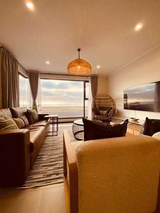 a living room with couches and a view of the ocean at Beachfront Townhouse - MowenOne in Walvis Bay