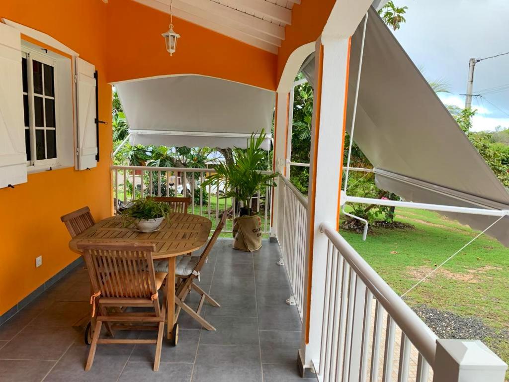 een veranda met een tafel en stoelen en een parasol bij Studio avec jardin et wifi a Le Moule a 5 km de la plage in Le Moule