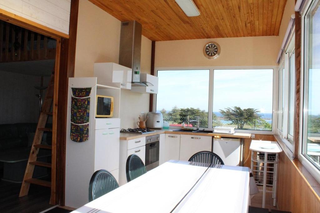 une cuisine avec des appareils blancs et une grande fenêtre dans l'établissement 756 - Chalet à Erquy avec vue mer à 200m de la plage et de l'îlot Saint Michel, à Beaumont