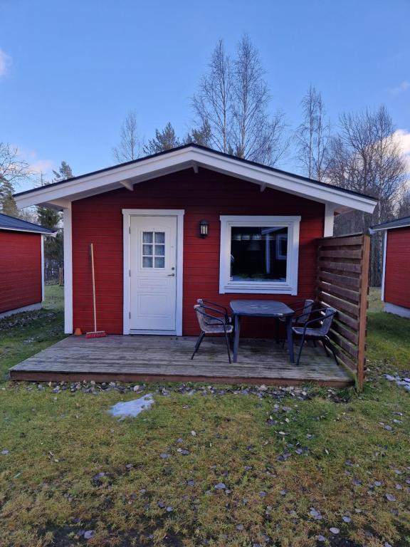 a red house with a table and chairs on a deck at Lovsjöbadens Camping in Jönköping
