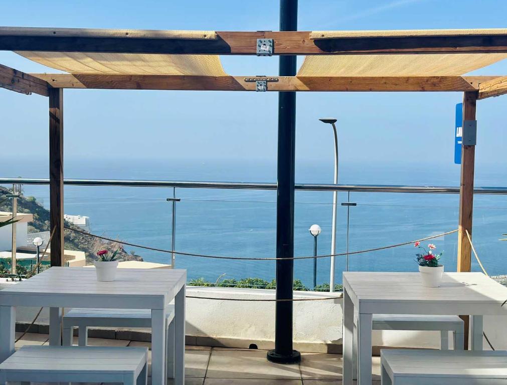 a patio with white tables and a view of the ocean at Holiday Club Vista Amadores in Amadores