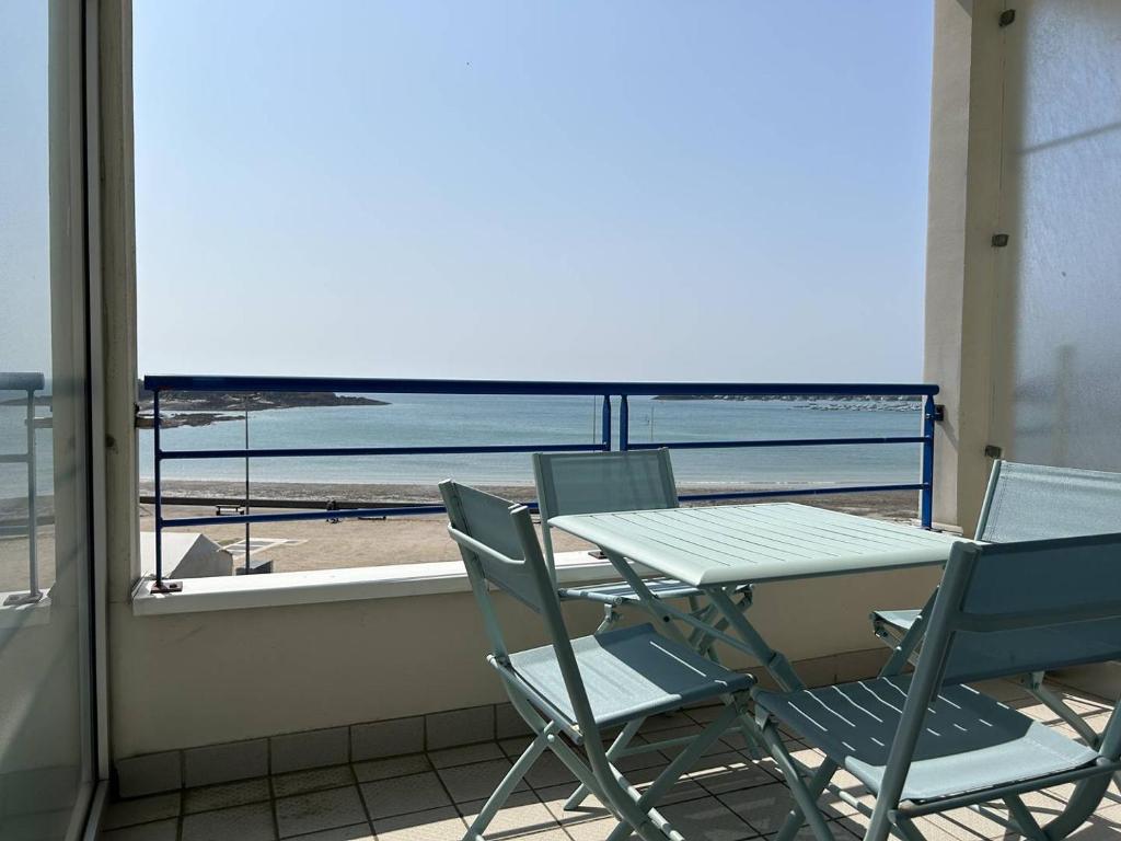 une table et des chaises sur un balcon avec vue sur la plage dans l'établissement 510 - Appartement T3 à Erquy avec pleine vue mer, à Erquy