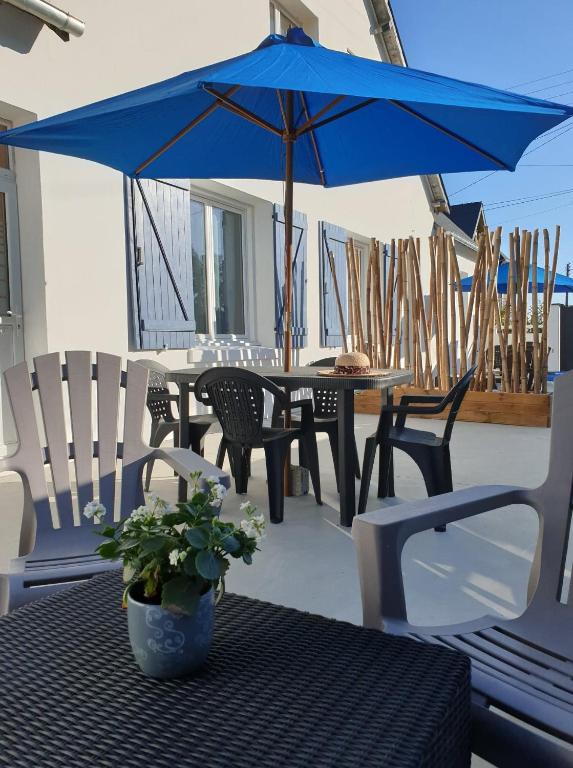 - un parasol bleu sur une table et des chaises sur une terrasse dans l'établissement Maison TYMAO de 14 personnes en bord de Mer, à Étables