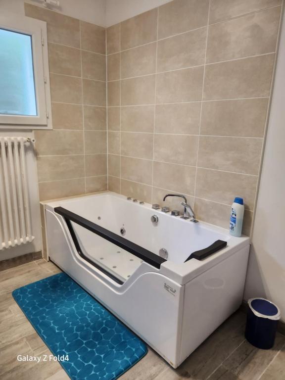y baño con bañera y alfombra azul. en Le Mazet, en Saint-Ambroix