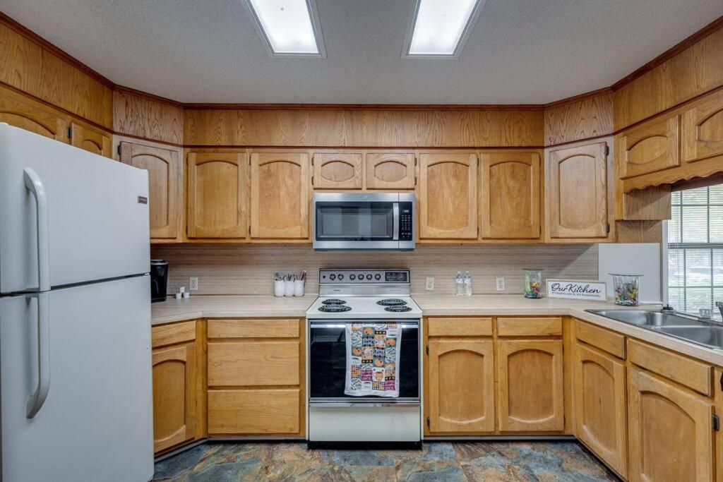 een keuken met houten kasten en een witte koelkast bij Rustic Flames & 4-Bedroom Comfort in West Monroe