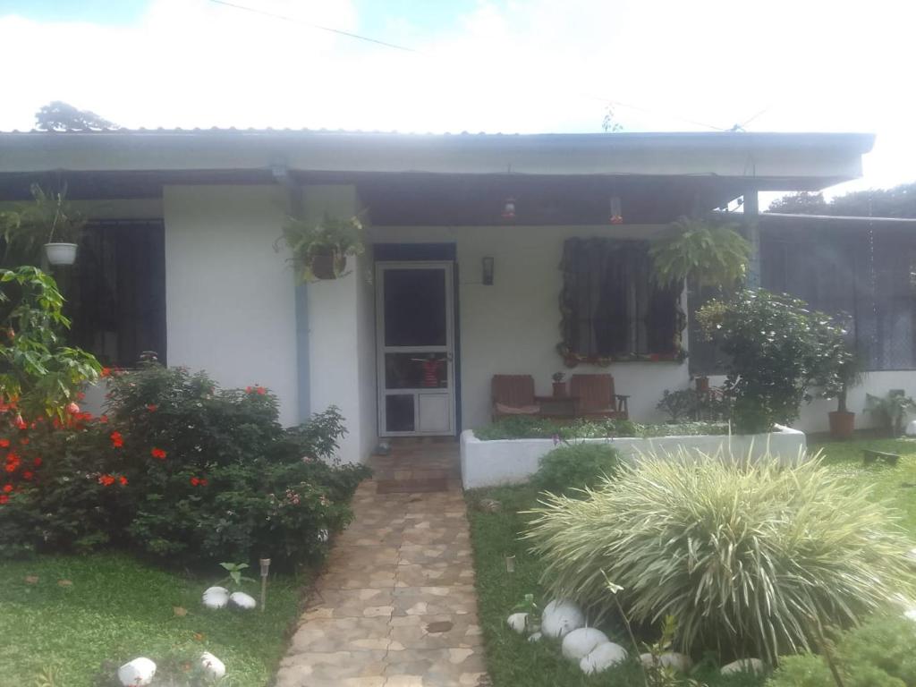 a white house with a patio and plants at Habitacion 2 Personas B&B in Nuevo Arenal