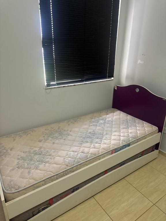 een klein bed in een kamer met een raam bij Casa da Denize in Cascavel