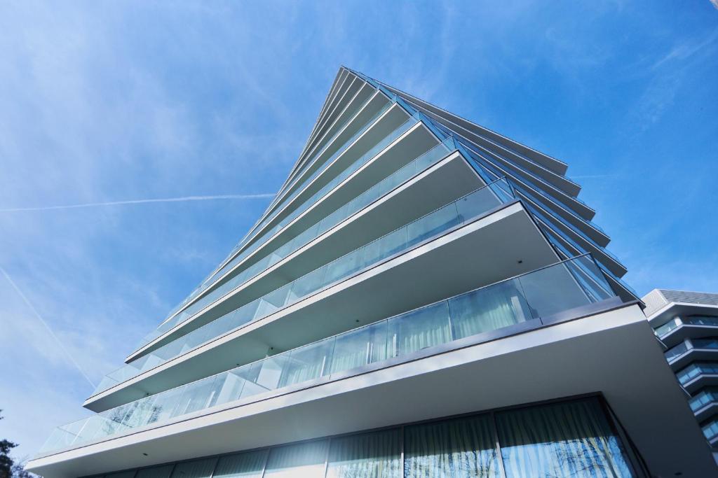 un edificio de cristal alto con un cielo azul en el fondo en Wave De Luxe Studio Resort&SPA 755B - Sea View en Międzyzdroje