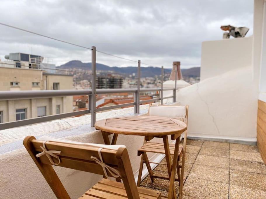 een houten tafel en 2 stoelen op een balkon bij DUPLEX - TERRASSE 2 CHAMBRES CENTRE-VILLE JAUDE in Clermont-Ferrand