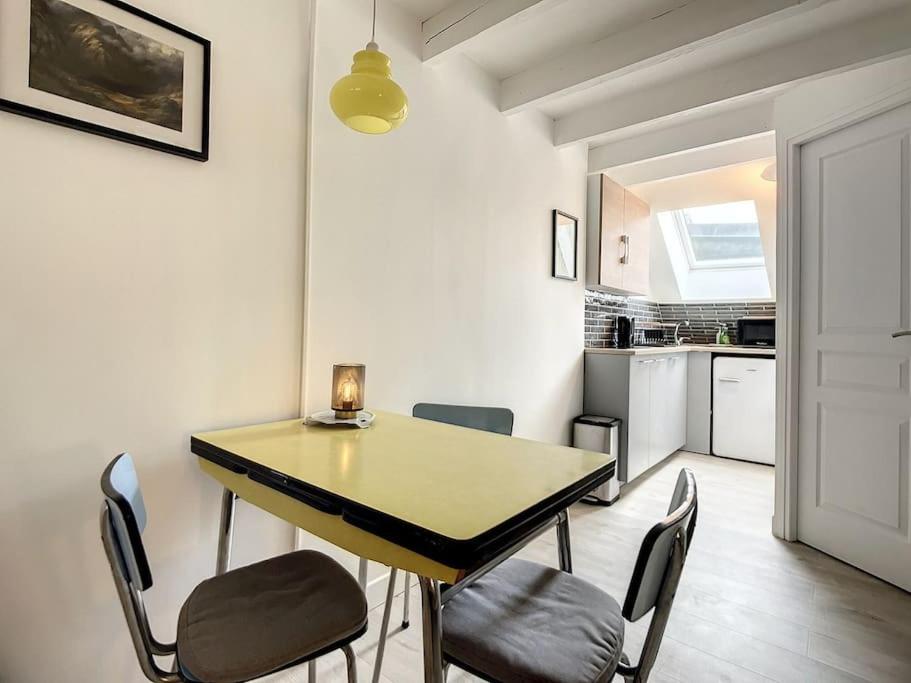 a dining room with a table and chairs and a kitchen at “Chez Mily“ Joli petit duplex plein centre Villers Cotteret in Villers-Cotterêts