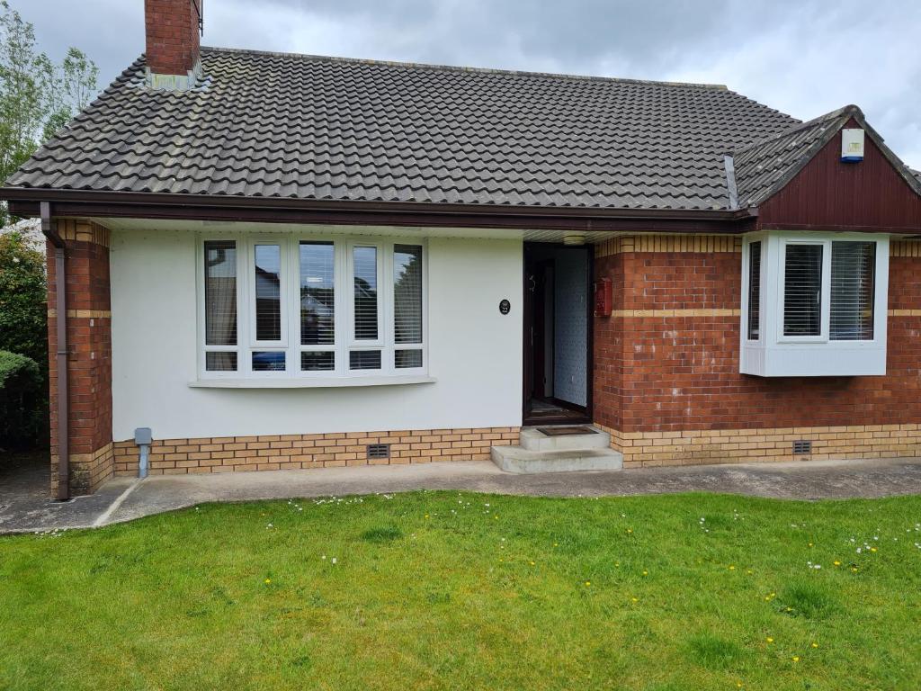 een stenen huis met witte ramen en een grasveld bij Willowfield in Coleraine