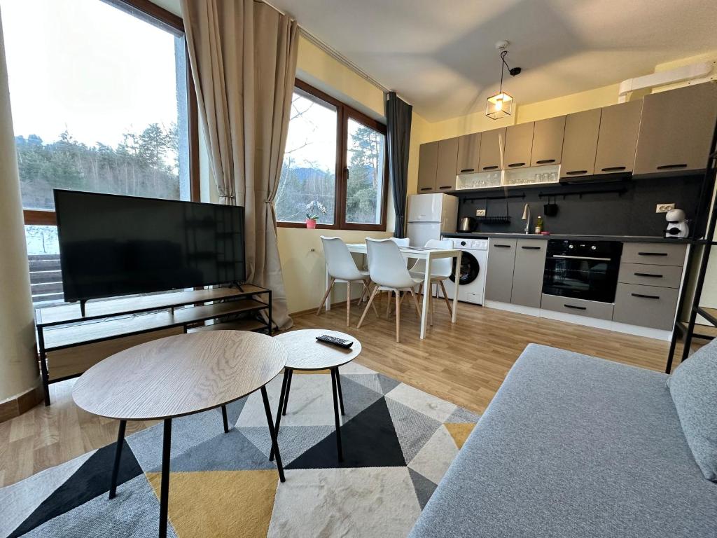 a living room with a kitchen with a table and a tv at Pine Tree - charming apartment in Bansko