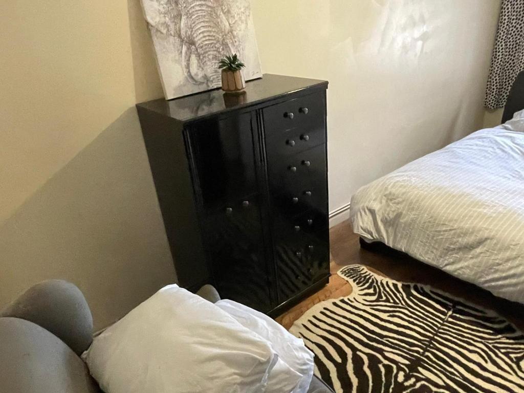 a bedroom with a bed and a dresser with a cactus on it at The Woodlands apartments 1 in London