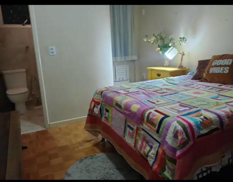 a bedroom with a bed with a colorful quilt on it at Suíte bem localizada em Vitoria in Vitória