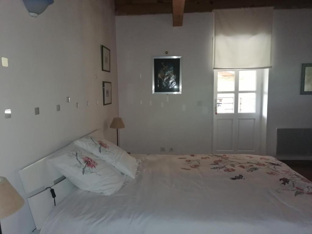 a white bedroom with a bed and a window at Chez Yvette & Shoji in Mauvezin