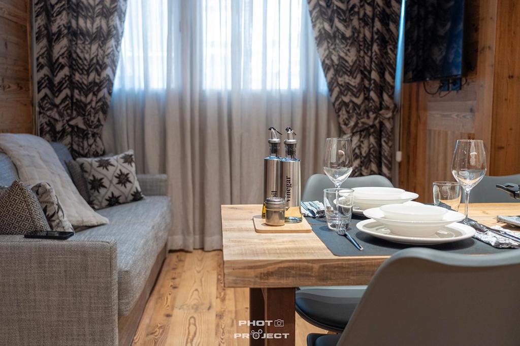 a dining room with a table with plates and wine glasses at Fior di Roccia Apartments- in centro Cervinia, sauna privata, Matterhorn dream in Breuil-Cervinia