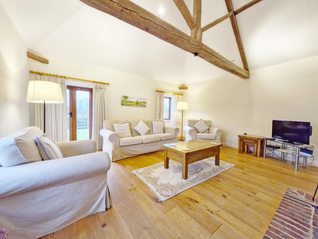 a living room with white furniture and a tv at The Run, West Lavant in Chichester