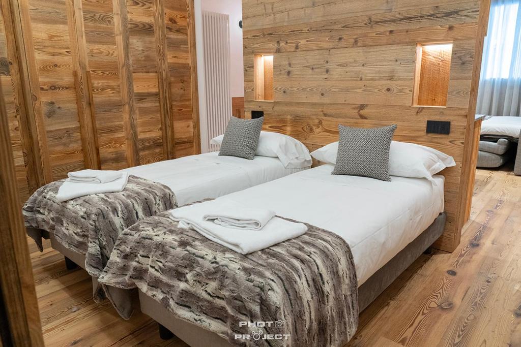 two beds in a room with wooden walls at Fior di Roccia Apartments- in centro Cervinia, sauna privata, Matterhorn dream in Breuil-Cervinia