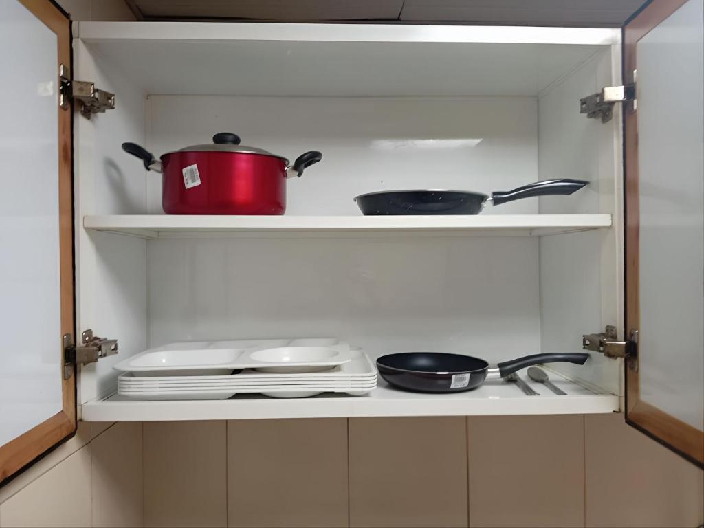 a cupboard with dishes and pots and pans at MBZ - Pleasant Stay in Abu Dhabi