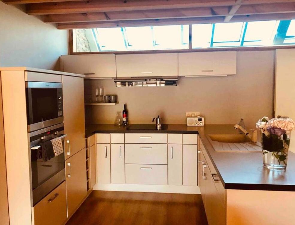 uma cozinha com armários brancos e uma grande janela em Duplex avec superbe vue boisée em Esneux