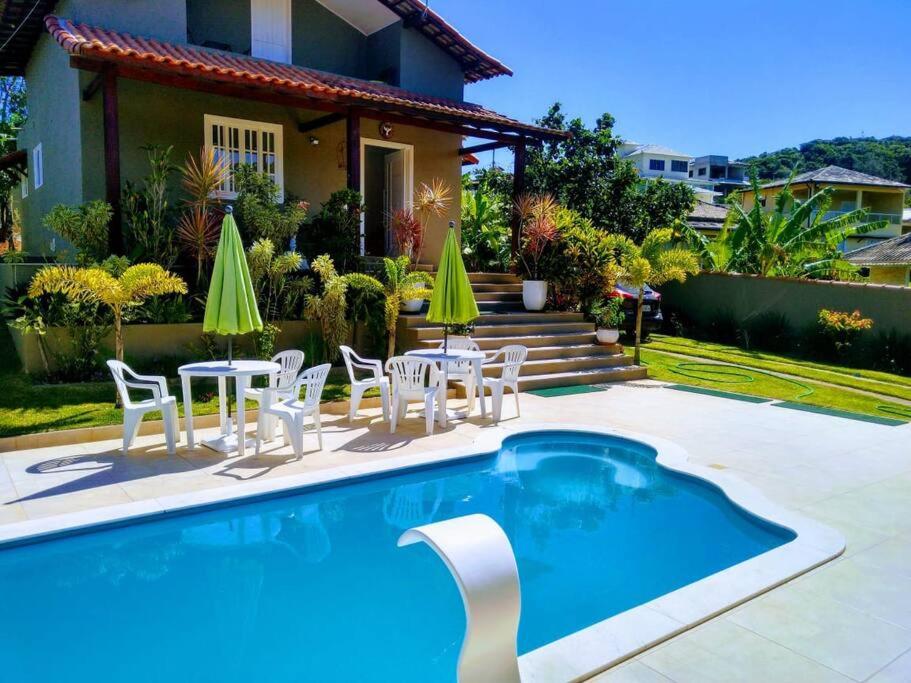 布希奧斯的住宿－Casa em Búzios，一个带桌椅的游泳池以及一座房子