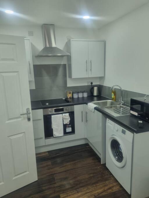 uma cozinha com armários brancos, um lavatório e uma máquina de lavar louça em 1 Bedroom Apartment em Daventry
