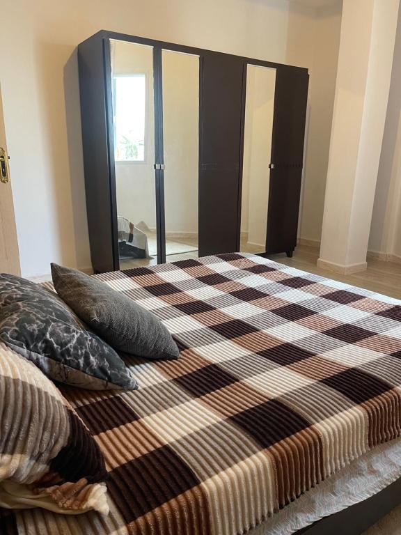 a bed with a checkered blanket and pillows on it at cosy Furnished appartment in Ez Zahra