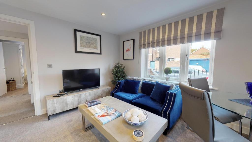 a living room with a blue couch and a tv at The Stratford Suite Dunara 6 in Leamington Spa