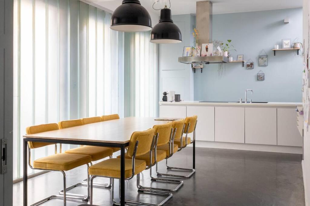 a dining room table with yellow chairs in a kitchen at Lightful architectural house in Ghent