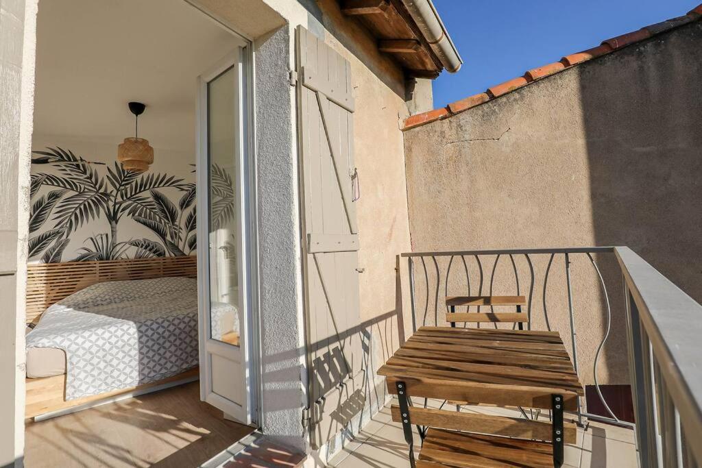 a wooden bench sitting on a balcony with a bed at Charmante petite maison de ville avec balcon in Fréjus