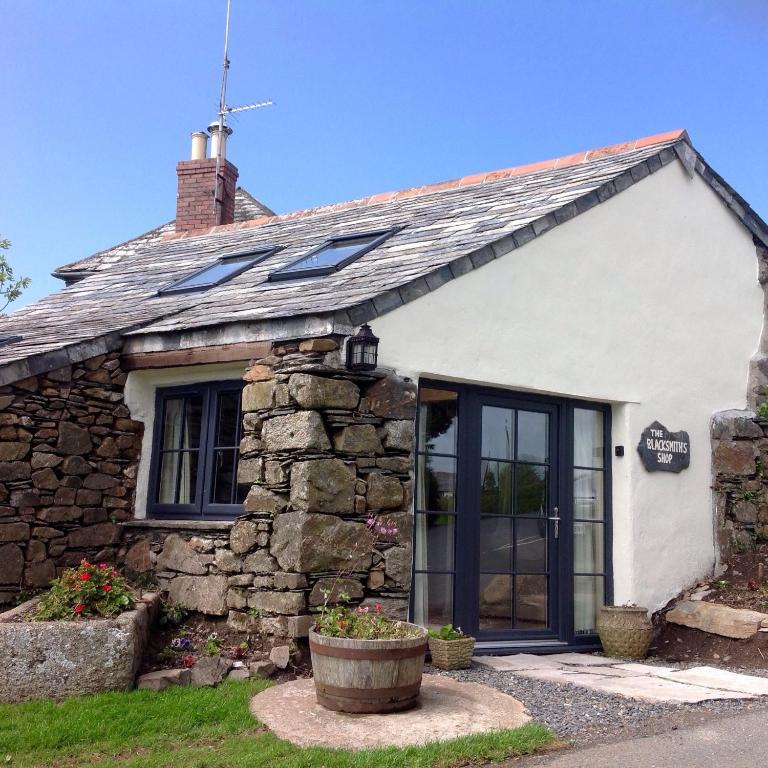 a stone cottage with black windows and a roof at The Blacksmith's Shop in Port Isaac